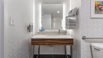 A modern bathroom with a vanity, mirror, towel rack, and a toilet.