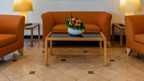 A lobby with a sofa, two lamps, a table with a vase of flowers, and a large abstract painting on the wall. - Schlosspark (Berlin)