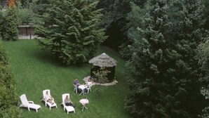 A grassy outdoor area with lounge chairs and a small thatched structure. - Schlosspark (Berlin)