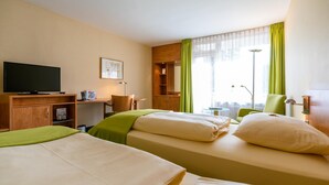 A hotel room with two beds, a television, a desk, and a chair. - Schlosspark (Berlin)