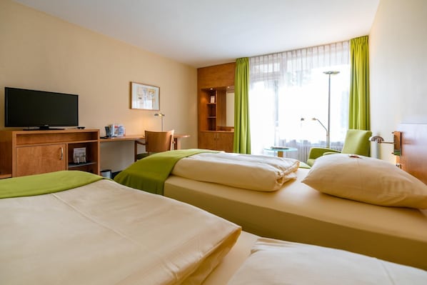 A hotel room with two beds, a television, a desk, and a chair.