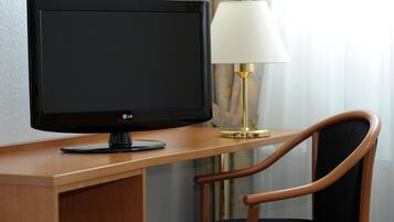 A wooden desk with a flat-screen LG monitor, a lamp, and a chair.