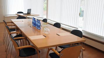 A conference room with a long table, chairs, a laptop, water bottles, and a glass pitcher.