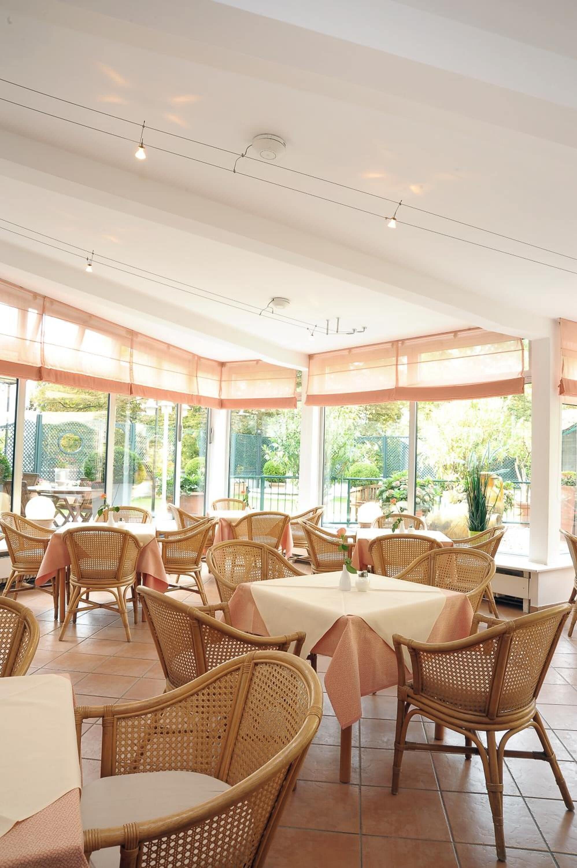 A restaurant with wicker furniture and large windows.
