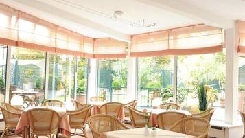 A restaurant with wicker furniture and large windows.