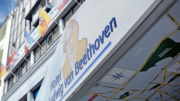 A hotel sign with a classical architectural design, featuring a prominent logo and a map of the city. - Hotel Ludwig van Beethoven (Berlin)