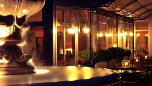 A well-lit indoor area with a large decorative fountain, glass doors, and several tables and chairs. - Hotel Ludwig van Beethoven (Berlin)