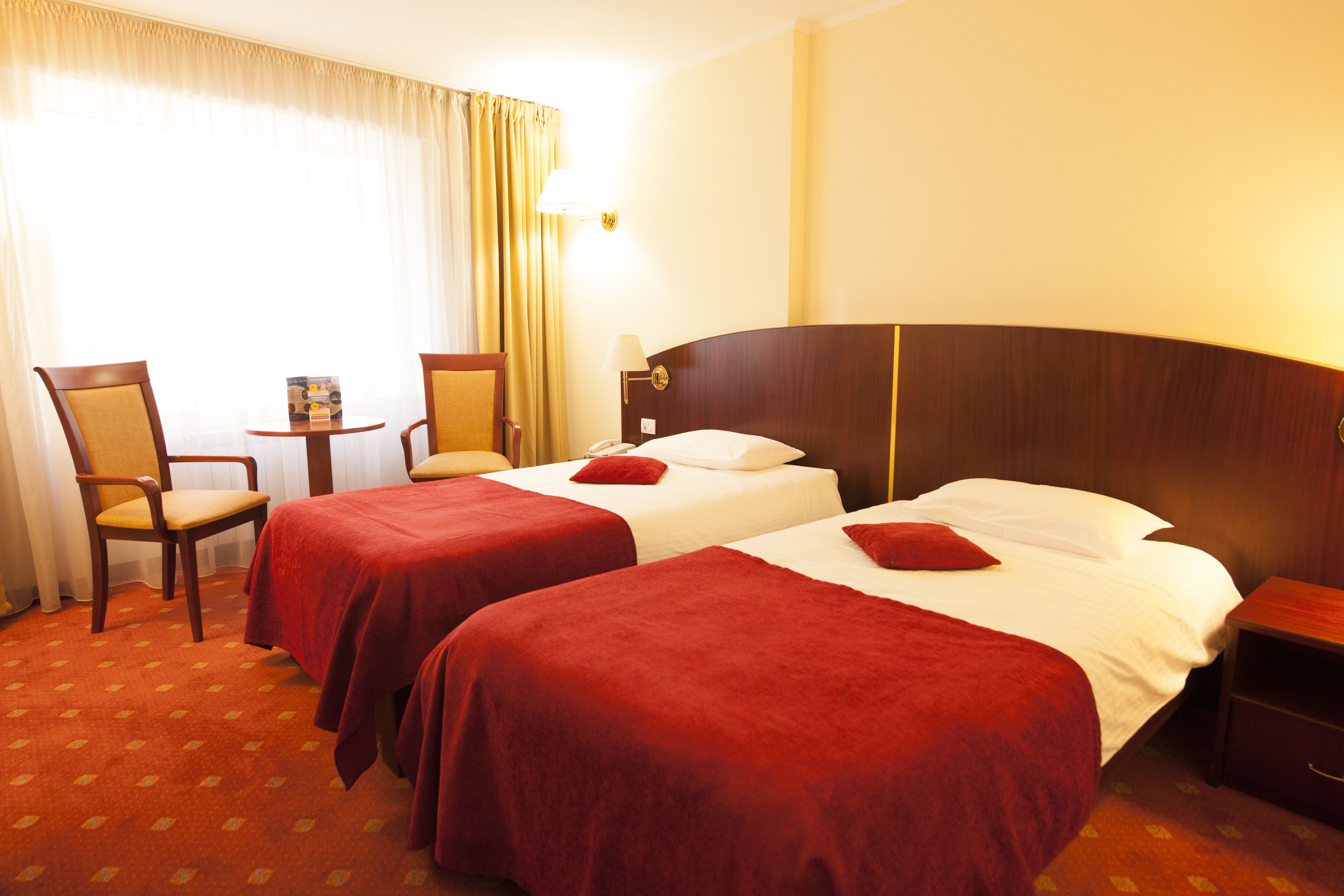 A hotel room with two beds, a desk, and a chair.