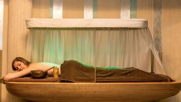 A wooden boat-shaped bed with a person lying on it, a bowl, and a cup.