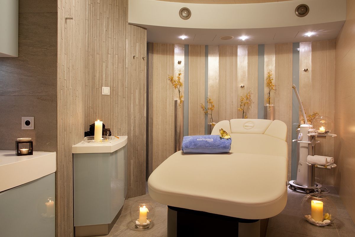 Et moderne spa-rum med massagestol, lille håndvask og dekorative lys.