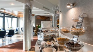 Un bufé de desayuno con diversas opciones de comida y un área de estar con mesas y sillas.