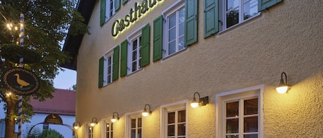 Zona de estar al aire libre frente a un edificio con el nombre "Gasthof" en la fachada.