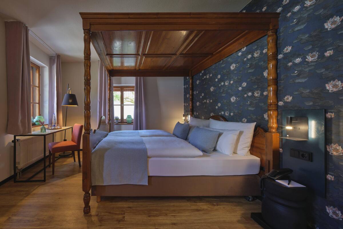 A four-poster bed with a wooden frame, a desk with a lamp, and a radiator.