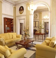 A spacious living room with a yellow sofa set, a wooden coffee table, and a vase with flowers.