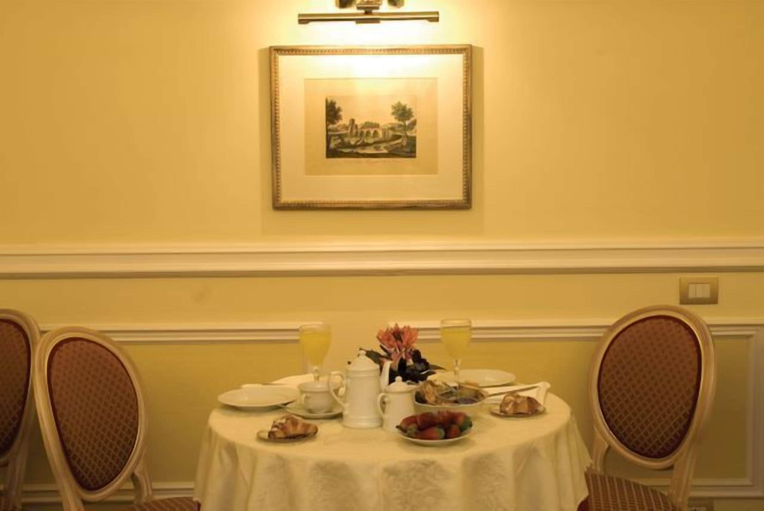 A dining table set with breakfast items, a framed picture on the wall, and two chairs.