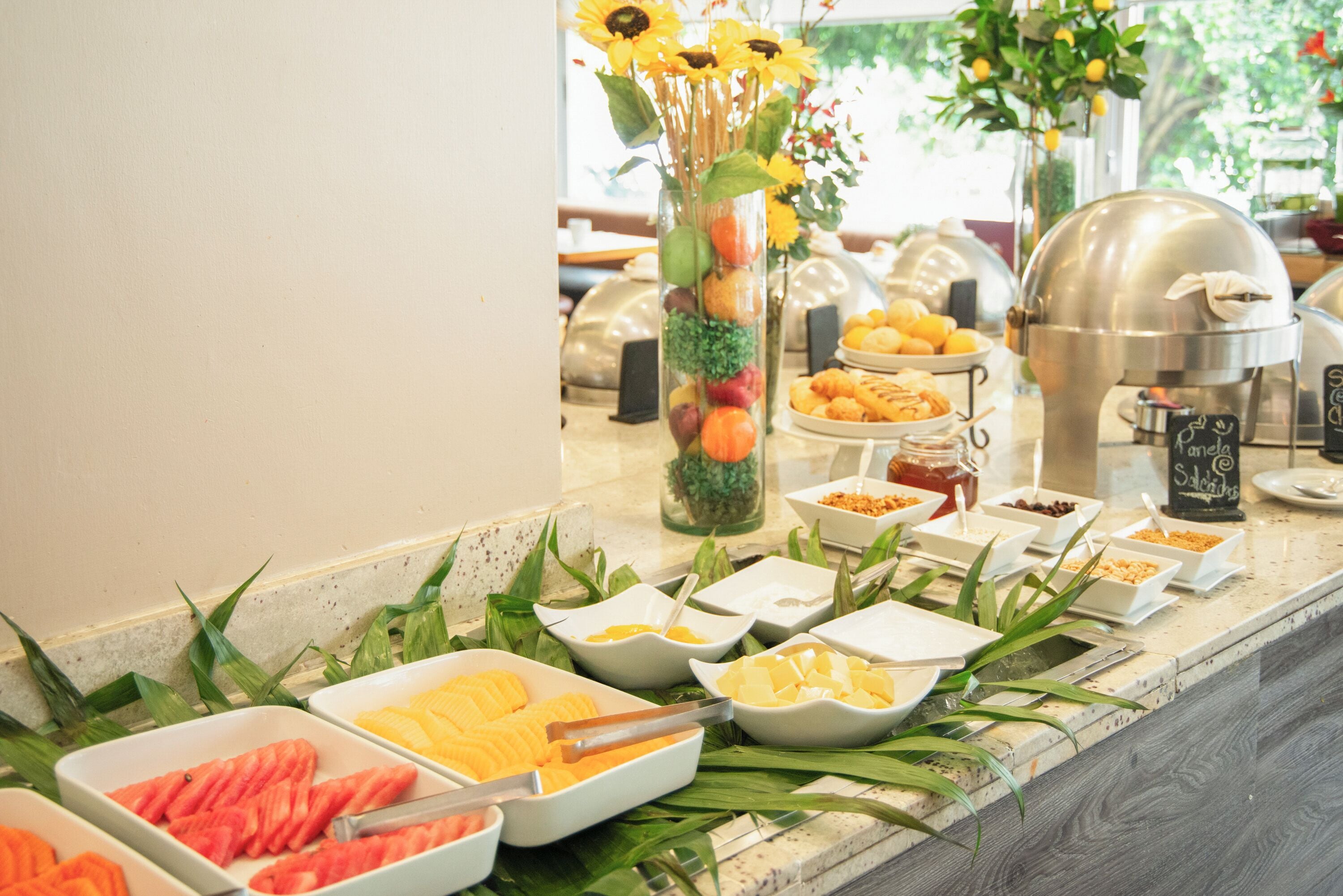 A buffet setup with various food items and a decorative vase with flowers.