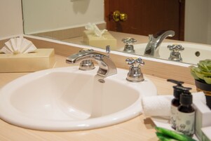Un lavabo con uno specchio sopra, un dispenser di sapone e un asciugamano.