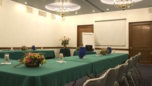 A conference room with green tables, chairs, and floral centerpieces. - Hotel Stanza (Mexico City)