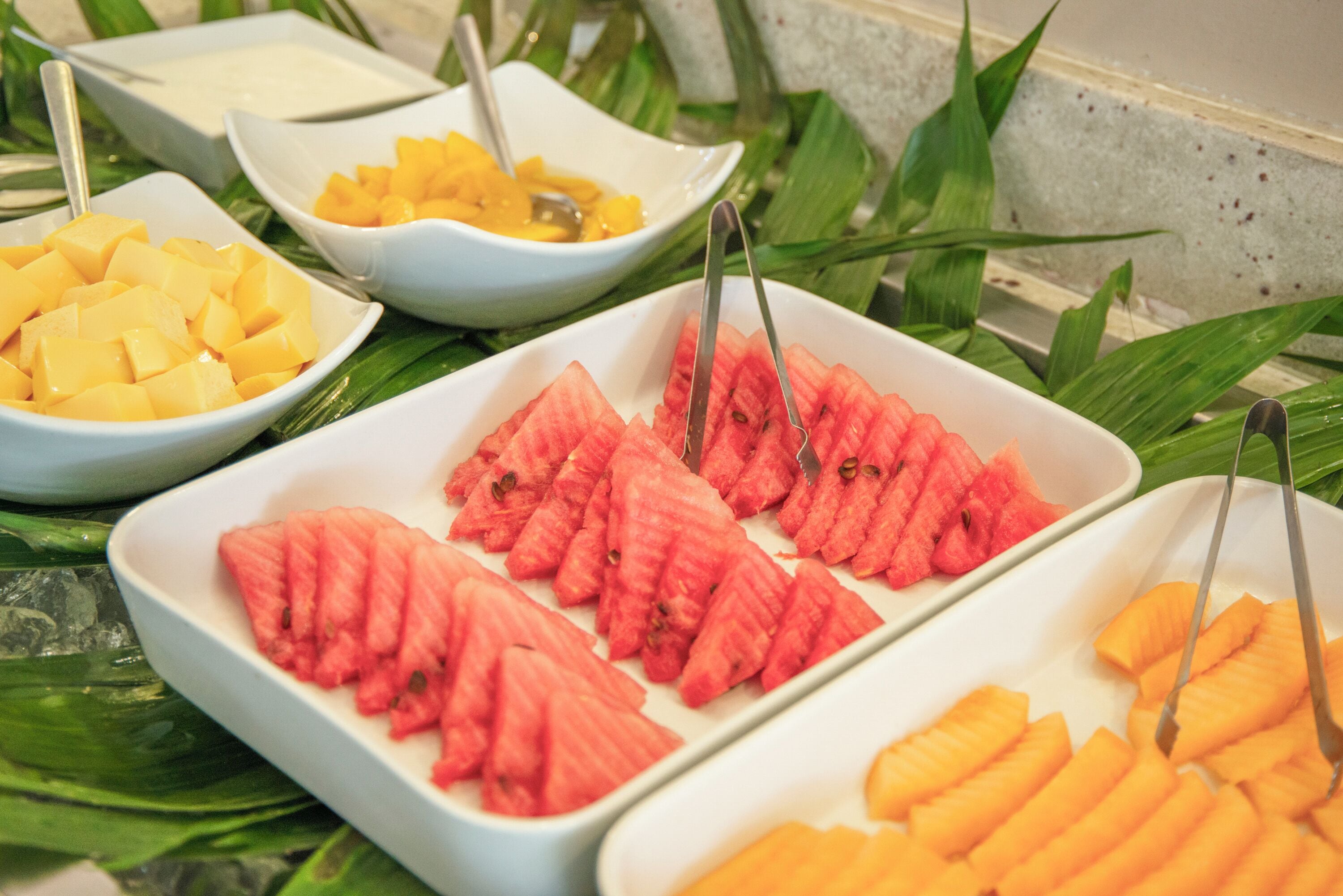 Un buffet con diversi tipi di frutta e una tovaglia bianca.
