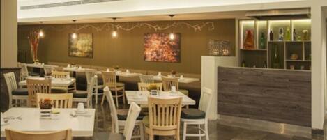 A restaurant with multiple tables and chairs, a counter with a menu display, and artwork on the walls.