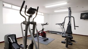A gym with various exercise equipment, including a treadmill, elliptical, and weight machines. - Hotel Stanza (Mexico City)