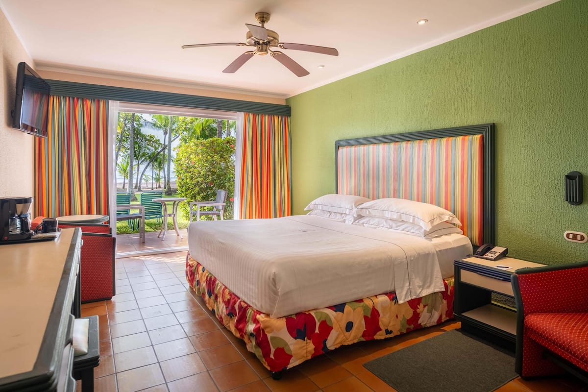 A hotel room with a bed, a desk, a chair, a phone, and a view of the outdoors.