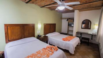 A room with two beds, a desk, a ceiling fan, and a mirror.