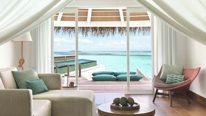 Ein Zimmer mit Meerblick, ausgestattet mit einer Couch, einem Sessel und einem kleinen Tisch mit Früchten.