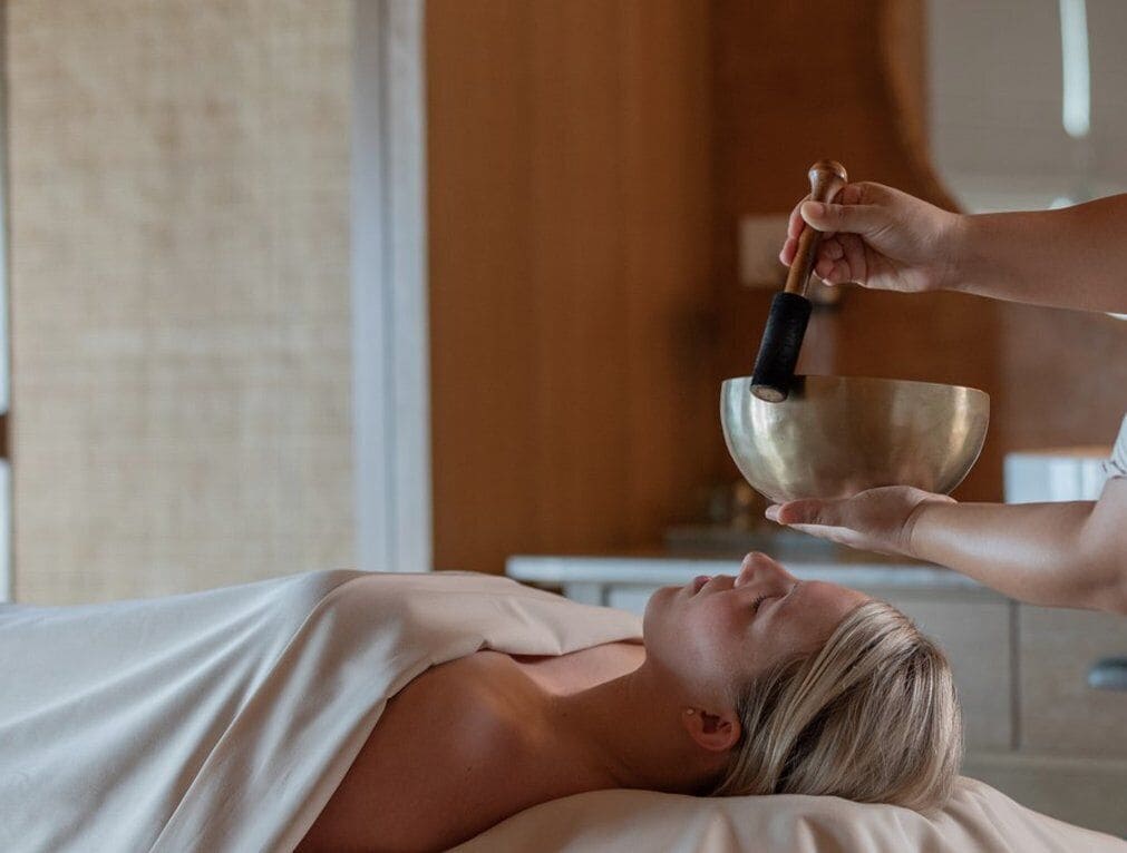Eine Person liegt im Bett und erhält eine Klangtherapie mit einer Gongs.