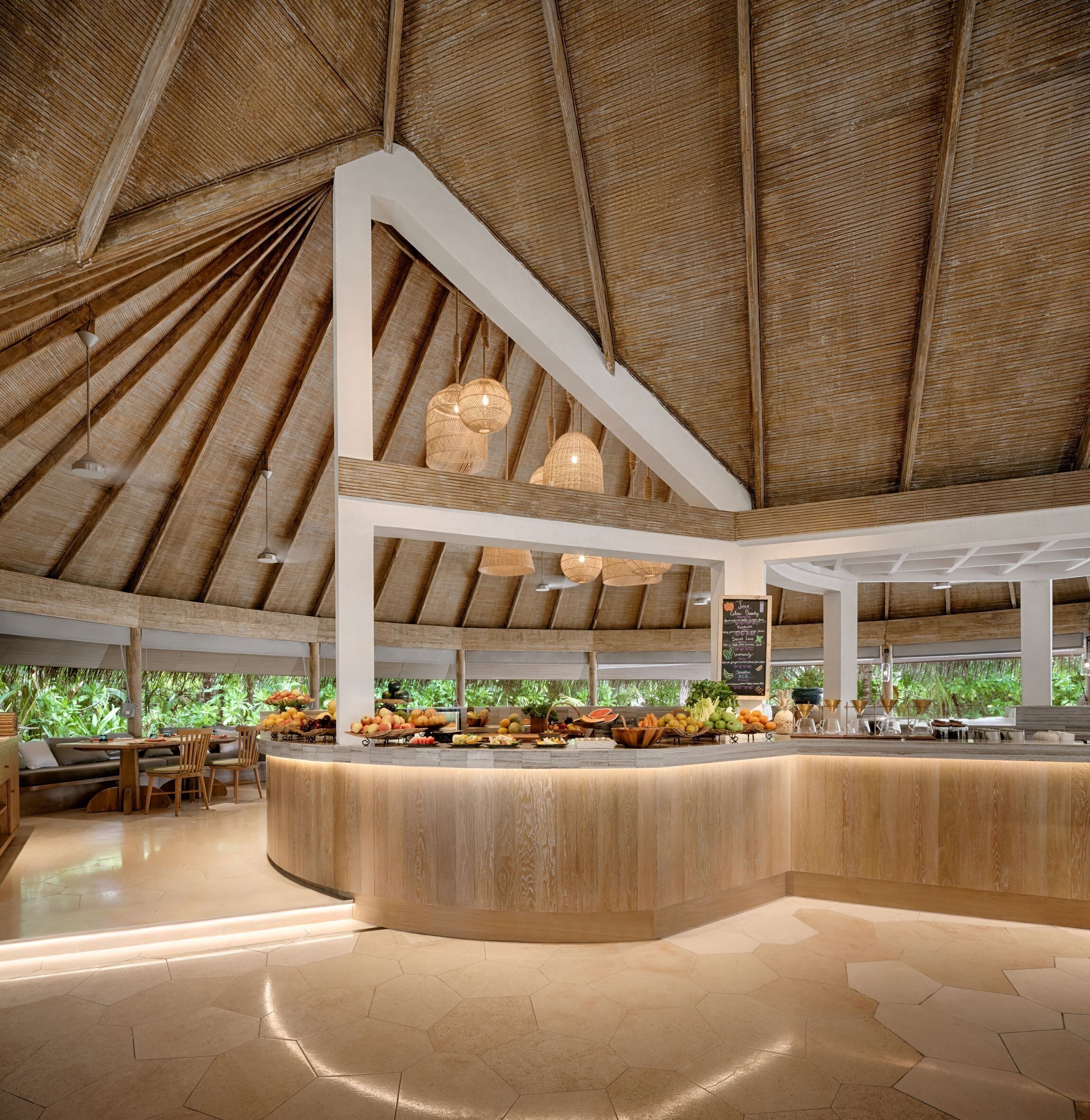 A spacious indoor area with a high ceiling and natural light, featuring a central counter with fresh produce and seating areas.
