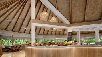 A spacious indoor area with a high ceiling and natural light, featuring a central counter with fresh produce and seating areas.