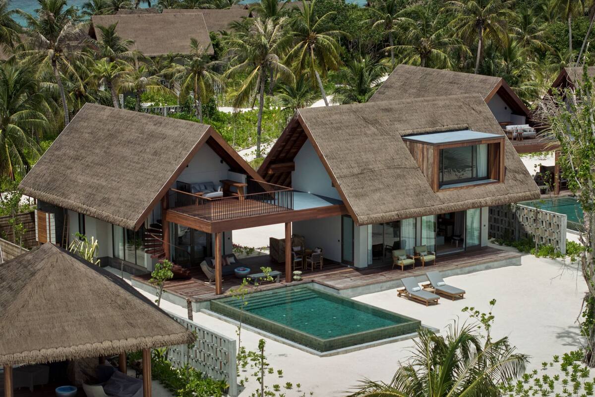Ein Resort mit strohgedeckten Villen, einem Pool und einer tropischen Umgebung.