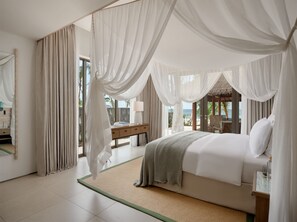 Enjoy ocean views from the large window in this serene bedroom featuring a comfortable bed, a desk, and a nightstand.
