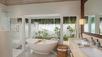 Un baño moderno con una bañera independiente, ducha a ras de suelo y un espejo grande.