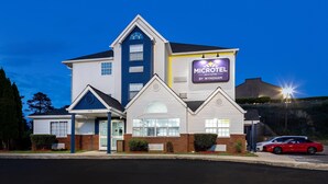 Edificio di un Microtel Inn & Suites con un cartello ben visibile, un garage e un'auto rossa parcheggiata davanti.