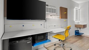 Una camera moderna con TV a schermo piatto, forno a microonde integrato e lavandino con specchio.