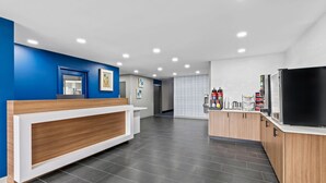 Una moderna area reception con scrivania in legno, parete decorata in blu e pavimento piastrellato.