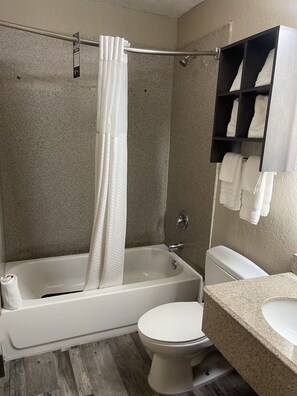 Un baño con bañera, inodoro y un perchero para toallas.
