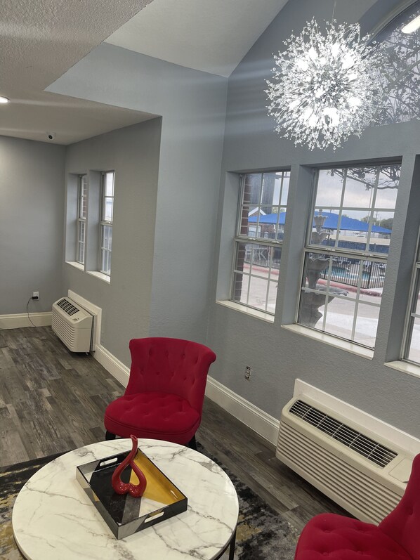 A room with grey walls, a red chair, a marble table, and a large window with a view of the outside.