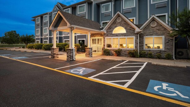 A multi-story hotel with a covered entrance, wheelchair-accessible parking, and a stone facade.