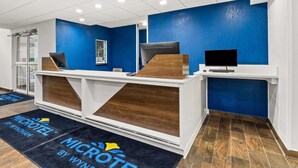 A reception area with a blue accent wall, a wooden reception desk, and a flat-screen monitor.