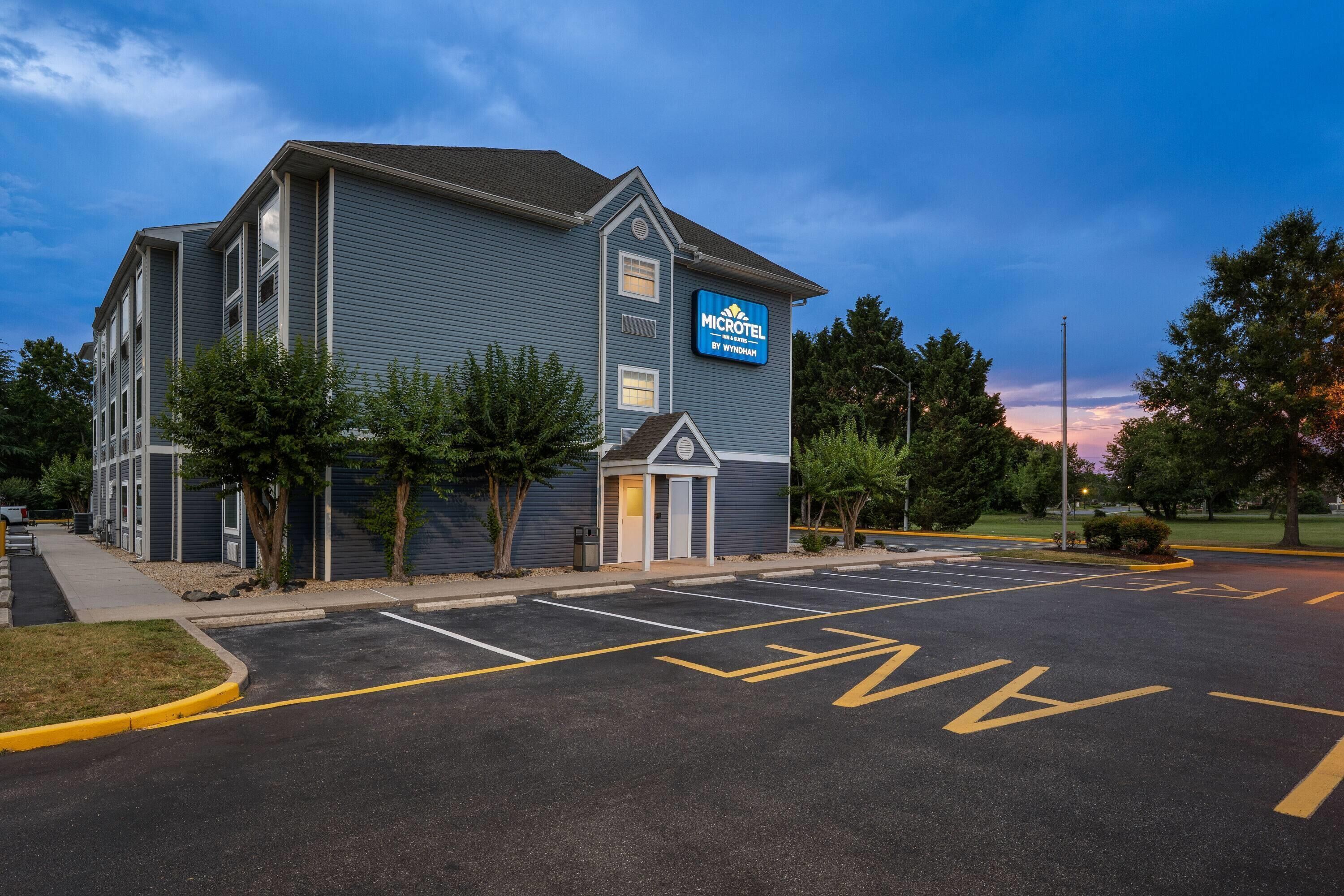 A Microtel by Wyndham hotel with a parking lot and a clear sky.