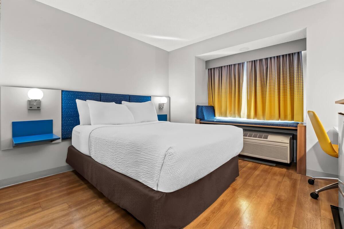 Et moderne hotelværelse med en stor seng, et skrivebord og en stol.