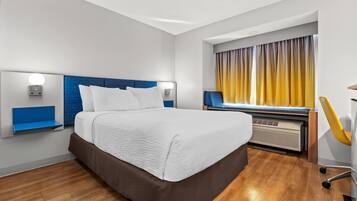 A modern hotel room with a large bed, a desk, and a chair.