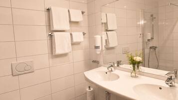 Un baño moderno con un lavamanos grande, un espejo y varios dispensadores de toallas.