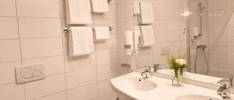 A modern bathroom with a large sink, mirror, and multiple towel dispensers.