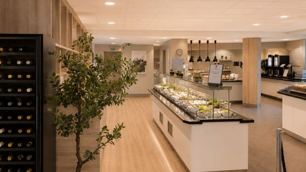 A hotel lobby with a buffet area, a wine rack, and a potted plant. - Haukeland Hotell (Bergen)