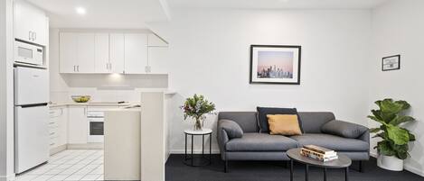 A modern living room with a grey sofa, a small coffee table, and a potted plant.