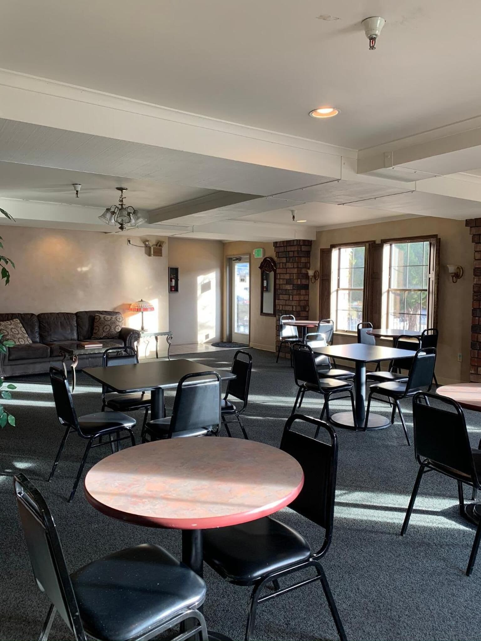 A spacious room with multiple tables and chairs, a sofa, and a fireplace.
