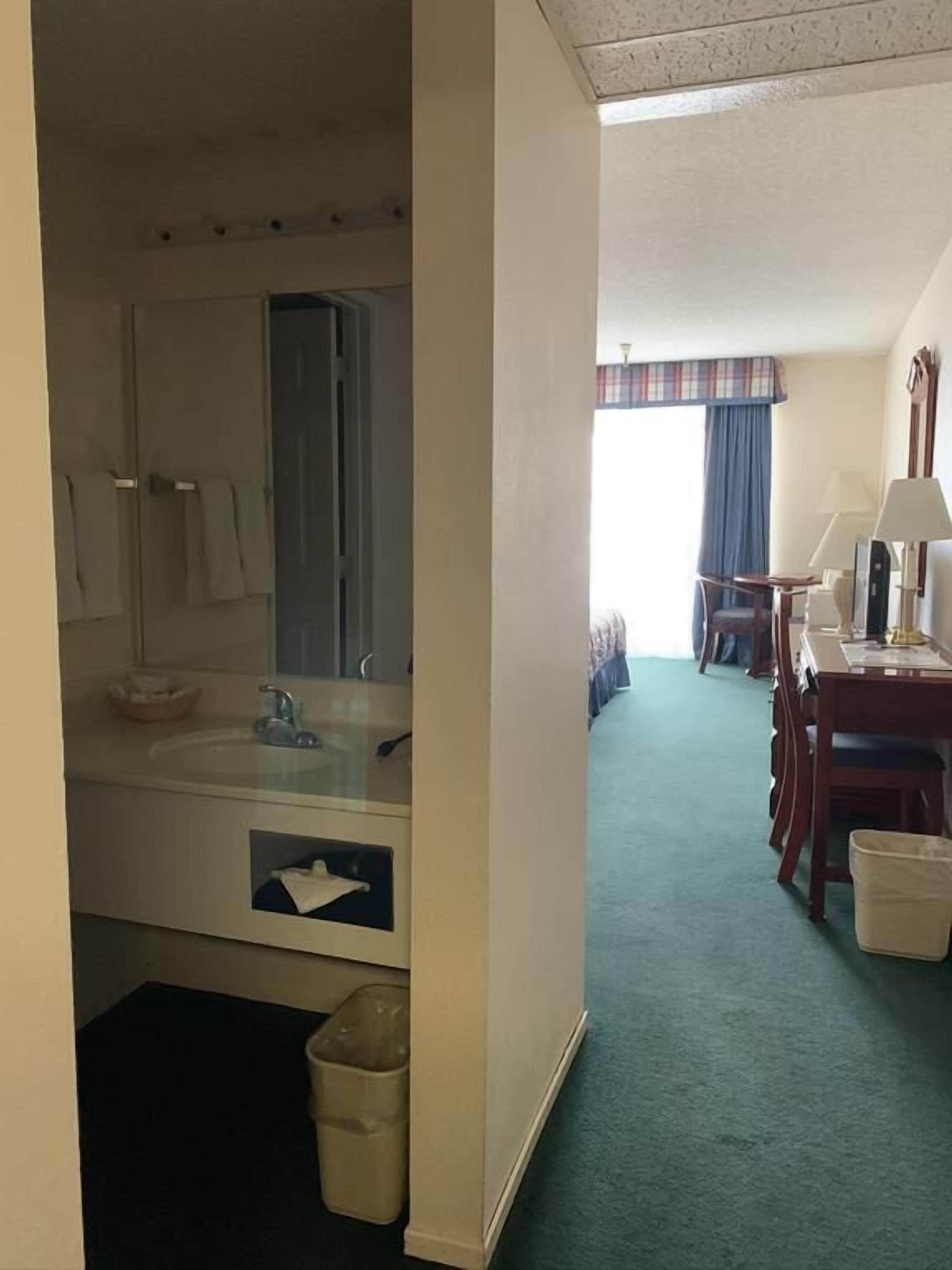 Una habitación de hotel con baño, zona de comedor y vistas al exterior.